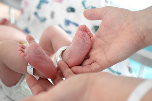 Baby, dem ein Patientenarmband am Fußgelenk angepasst wird