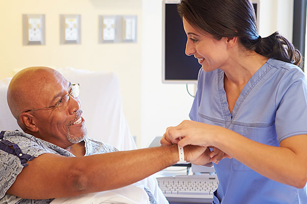 Infirmière plaçant un bracelet au poignet d'un patient âgé